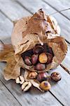 Roasted chestnut in a papper bag on old wooden table.