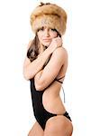 Young woman in black swimsuit and fur-cap warming herself.  Isolated