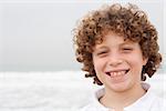 Happy young boy standing on sea background