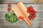 Cherry tomatoes on cutting board over wooden table background