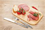 Prosciutto, salami, bread, vegetables and spices. Over wooden table background