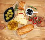 Fresh cheese, bread olives and tomatoes on wooden table background. Above view