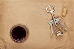 Wine glass, cork and corkscrew with red wine stains on brown paper background