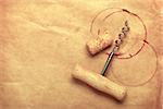 Cork and corkscrew with red wine stains on brown paper background with copy space