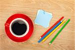 Blank post-it with office supplies and coffee cup on wooden table. Above view