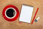 Blank notepad with office supplies and red coffee cup on wooden table. Above view