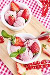 Homemade strawberry ice cream decorated with fresh berries and mint, top view