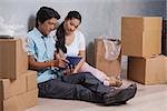 Happy couple sitting on floor using tablet in their new home