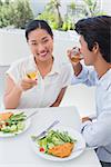 Happy couple having a meal together with white wine outside on a balcony
