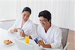 Couple in bathrobes shopping online in the morning at home in the living room