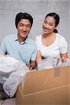 Happy couple sitting on floor unpacking boxes in their new home