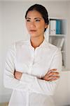 Casual businesswoman with arms crossed in her office