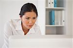 Casual businesswoman concentrating at her desk in her office