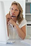 Casual businesswoman thinking at her desk in her office