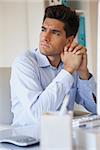 Casual businessman thinking at his desk in his office