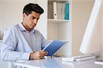 Casual businessman using his tablet at his desk in his office