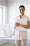 Casual businesswoman smiling at camera holding folder in the office