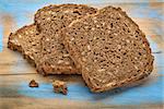 slices of organic, whole grain, dark rye bread on painted wooden cutting board