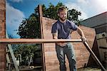 Joiner in backyard lifting wood framework