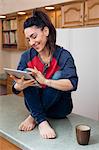 Young woman in kitchen using digital tablet