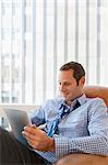 Mid adult man relaxing at home with digital tablet