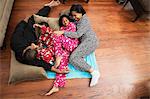 Mid adult couple and children playing on floor cushions