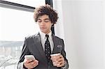 Young man using cell phone with coffee