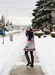 Young woman walking down snow covered street