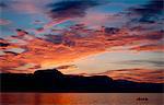 Silhouetted family paddling a canoe over Okanagan Lake, Naramata, British Columbia, Canada