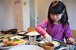 Girl selecting meal from dishes on dining table