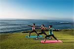 Women on cliff, in yoga positions