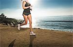 Mid adult woman jogging along cliff