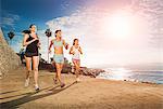 Mid adult women jogging along cliff