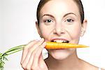 Young woman biting into carrot, portrait