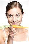 Young woman balancing carrot on hand, portrait