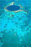 Central America, Belize, Lighthouse atoll, the Great Blue Hole, aerial shot of a dive boat leaving the Blue Hole. The hole is a marine cenote - a sunken cave in the Lighthouse atoll, part of the World Heritage listed Belize Barrier Reef System