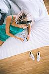 Overhead view of gorgeous blonde listening to music in bright bedroom