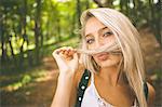 Content gorgeous blonde holding hair over mouth in the woods