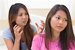 Two quarrelling sisters sitting on a couch in the living room