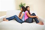 Two angry sisters sitting on a sofa in the living room