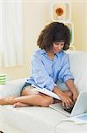 Pretty content student taking notes using laptop in bright living room
