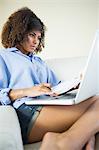 Pretty calm student making notes and using laptop in bright living room