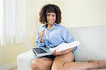 Pretty cheerful student making notes and using laptop in bright living room