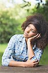 Gorgeous pensive brunette sitting at picnic table in nature