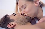 Cute blonde woman kissing her boyfriend with closed eyes