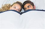 Beautiful woman hiding under a blanket with her boyfriend in their bed