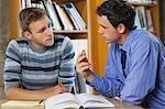 Lecturer explaining something to attentive student in library in a college