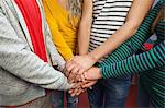 Close up of students holding hands together in hallway in a college