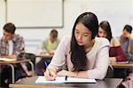 Focused asian student taking notes in class at the university