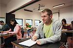 Smiling male student listening in class at the university